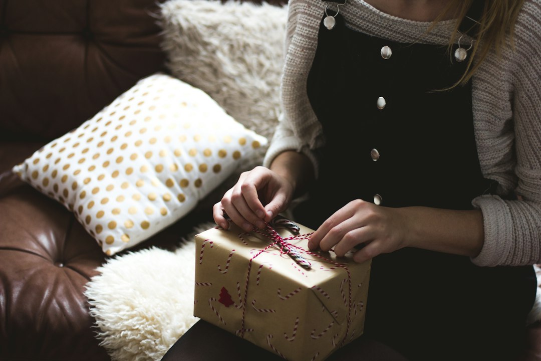 A woman at home thoughtfully opening a gift, reflecting on what makes Christian gift-giving meaningful — Nordenzi