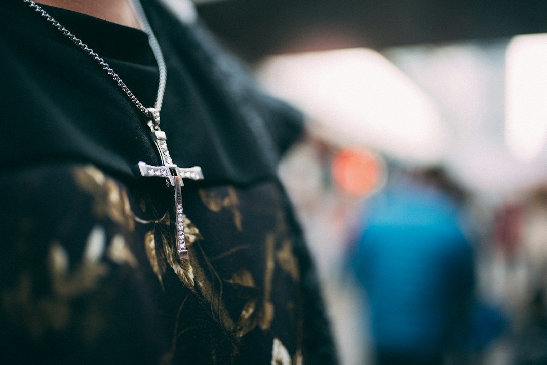 A person wearing a cross necklace close up, a quiet everyday sign of Christian faith - Nordenzi