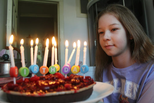 Teenage girl smiling at a candlelit birthday cake, celebrating her Sweet 16 — Nordenzi Christian Sweet 16 gift guide