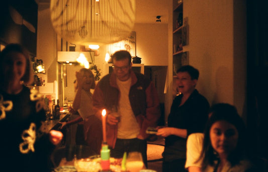 A family gathers around a lit candle during an at-home celebration after a baby's baptism — Nordenzi christian baptism gifts guide