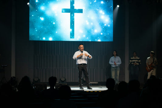 A pastor preaching from the pulpit beside a large cross, the quiet, faithful leadership Pastor Appreciation Month honors