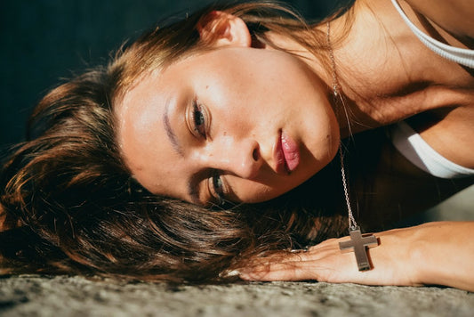 A woman wearing a cross necklace in warm natural sunlight — Nordenzi guide to choosing the right faith jewelry piece