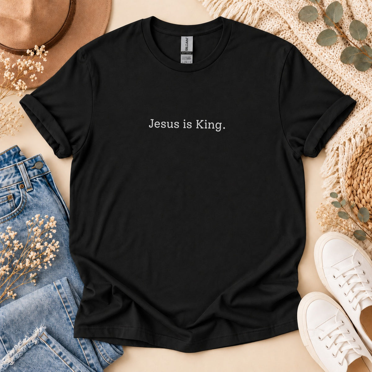 Black t-shirt with "Jesus is King." text, laid flat with jeans and sneakers.