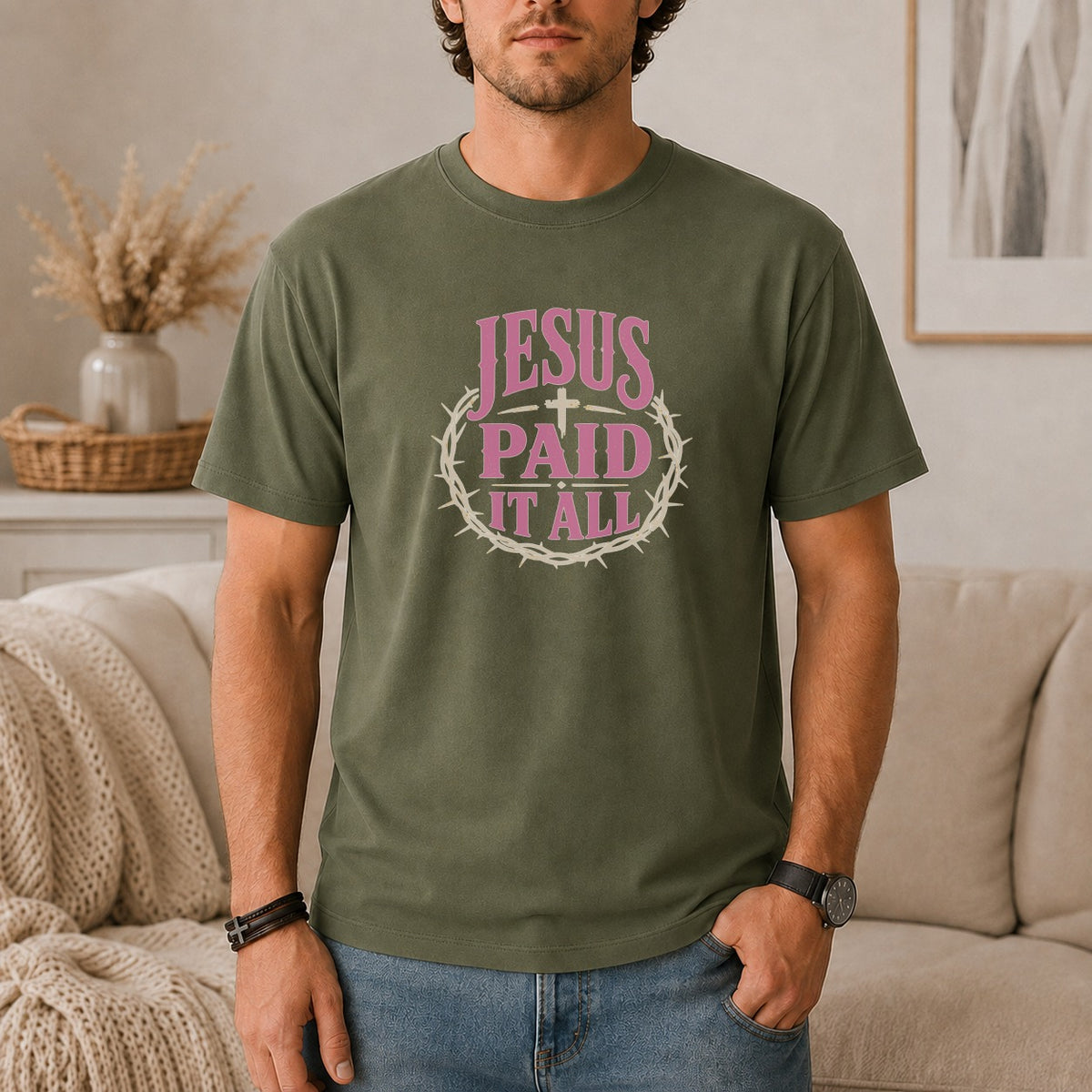 Olive green t-shirt with pink text "JESUS PAID IT ALL" and a crown of thorns graphic.