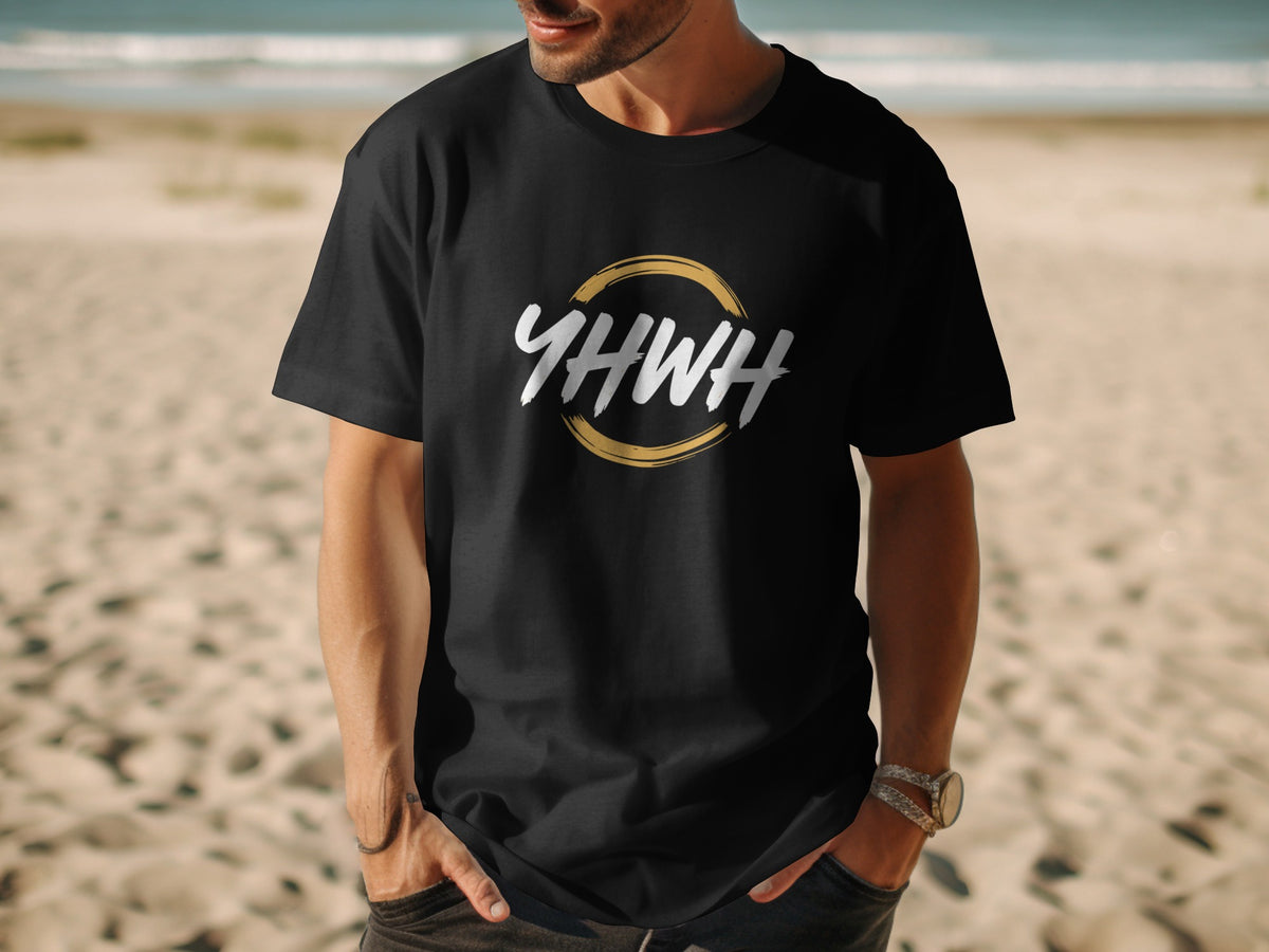 Black t-shirt with "YHWH" text inside a gold circle on a beach.