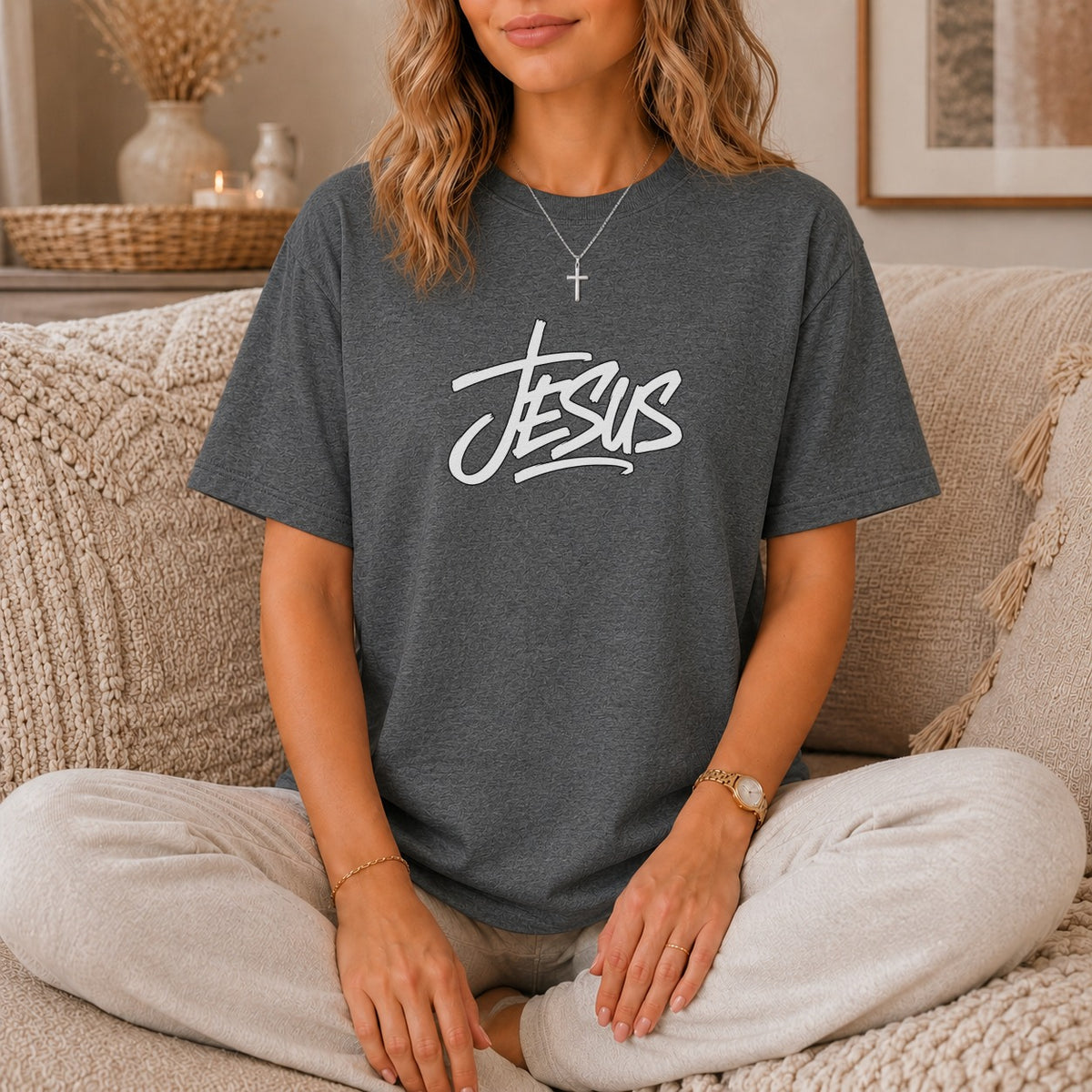 Dark gray t-shirt with white "Jesus" text and a cross necklace worn by a woman.