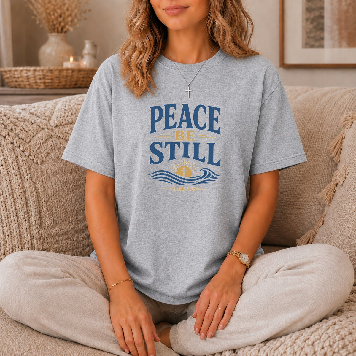 Grey t-shirt with "PEACE BE STILL" text and a sun rising over waves.