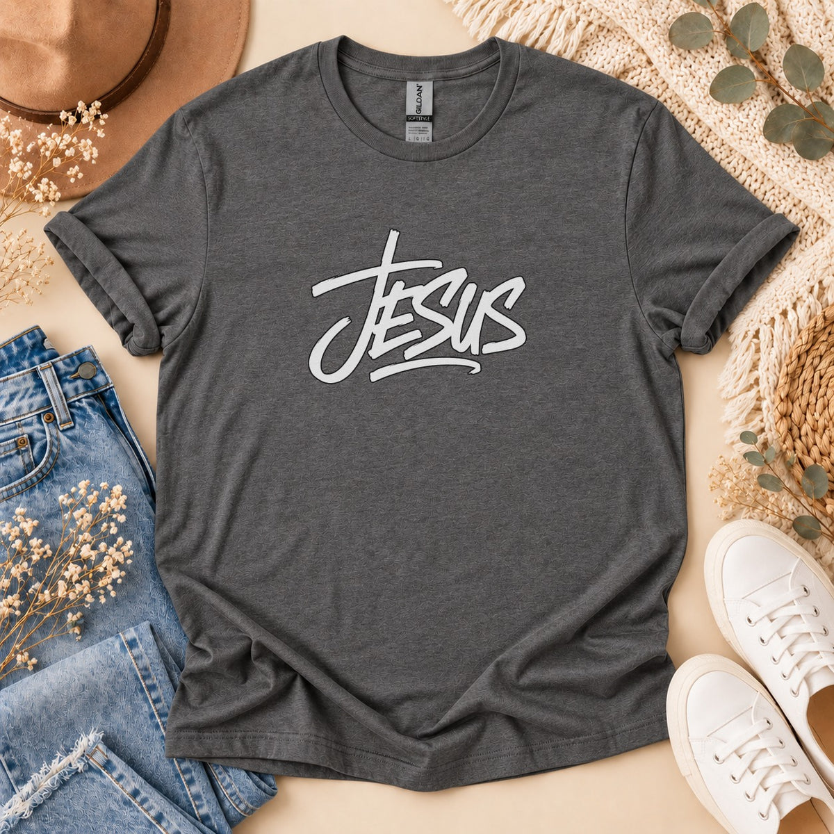 Dark grey t-shirt with white "Jesus" graphic, laid flat with jeans and sneakers.