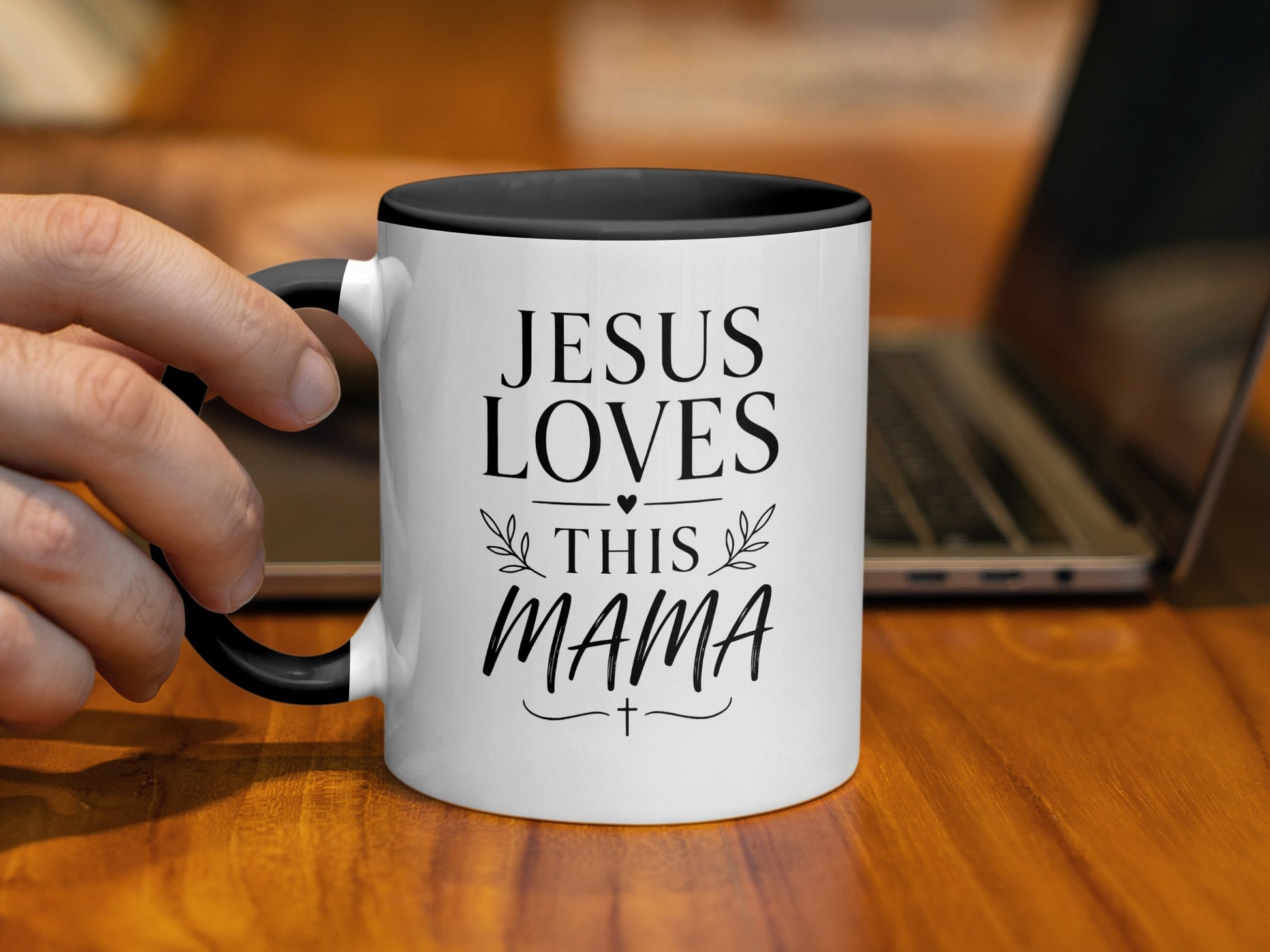 White mug with black rim reads "Jesus Loves This Mama" with decorative accents.