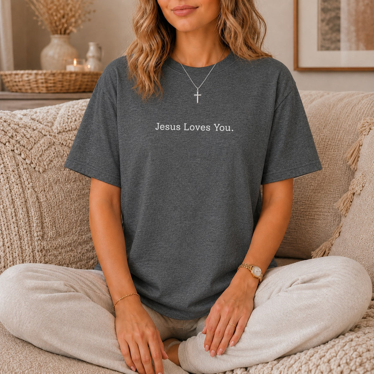 Dark grey t-shirt with white text "Jesus Loves You" and a cross necklace.