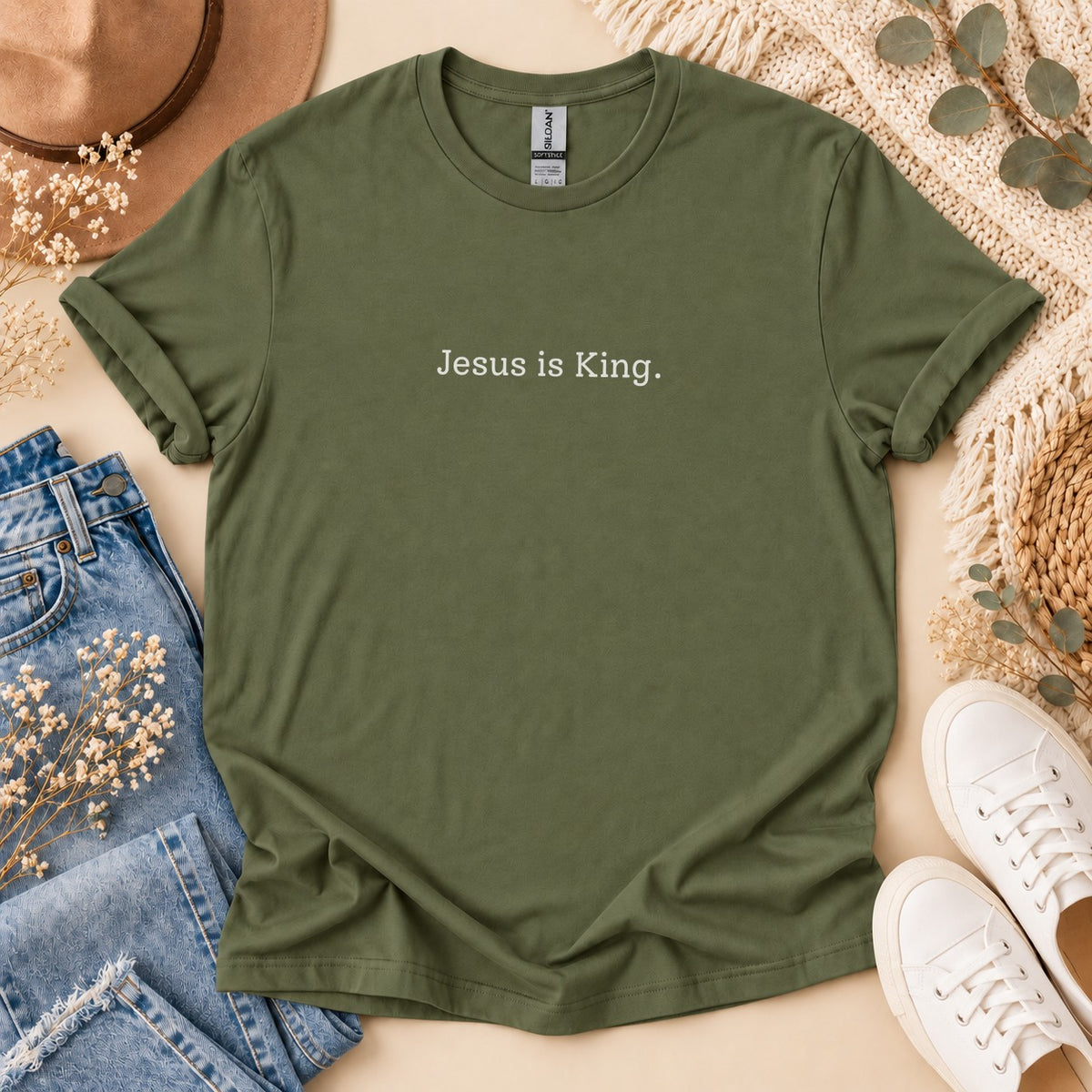 Olive green t-shirt with "Jesus is King." text, styled with jeans and sneakers.