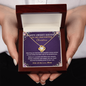 Hands holding a luxury gift box with a gold Sweet 16 love knot necklace
