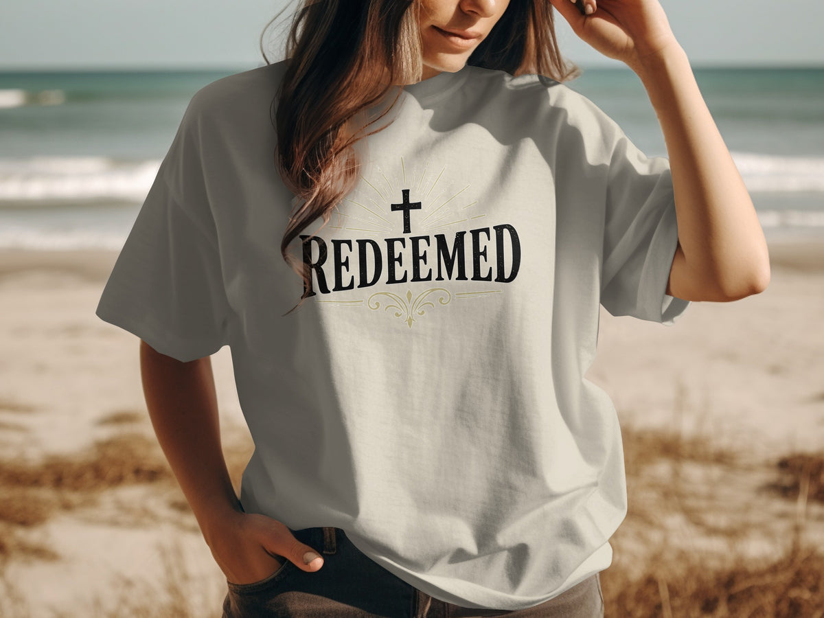 T-shirt with "Redeemed" and a cross graphic on a beach.