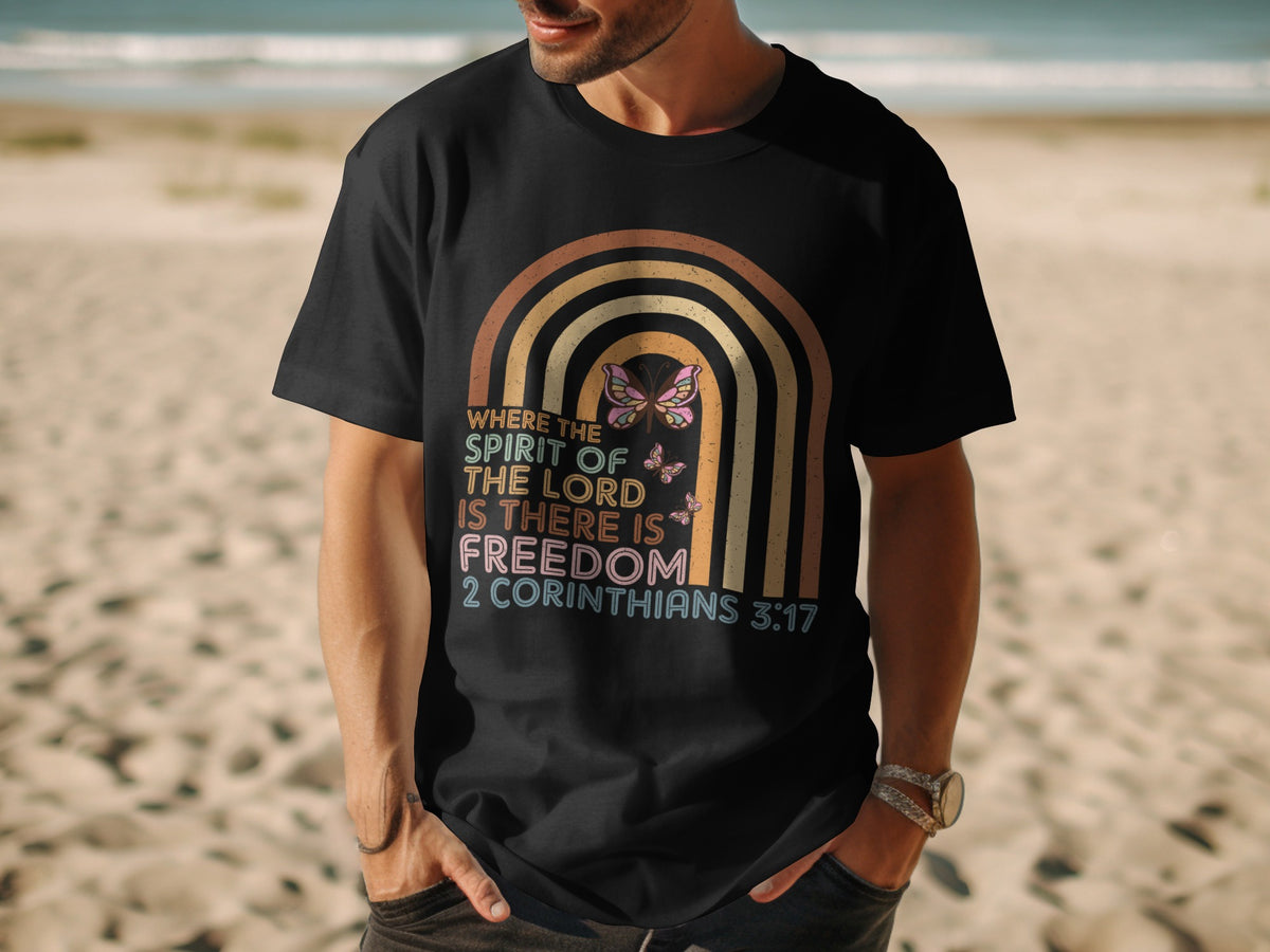 A person wearing a black t-shirt printed with a retro rainbow, butterflies, and scripture text.