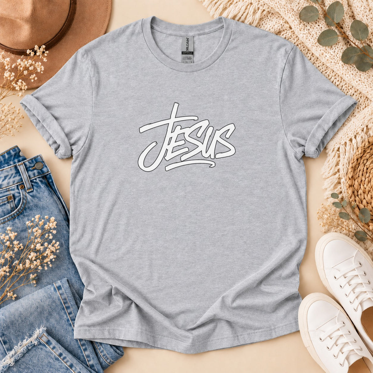 Grey t-shirt with white "Jesus" text graphic, laid flat with jeans and shoes.